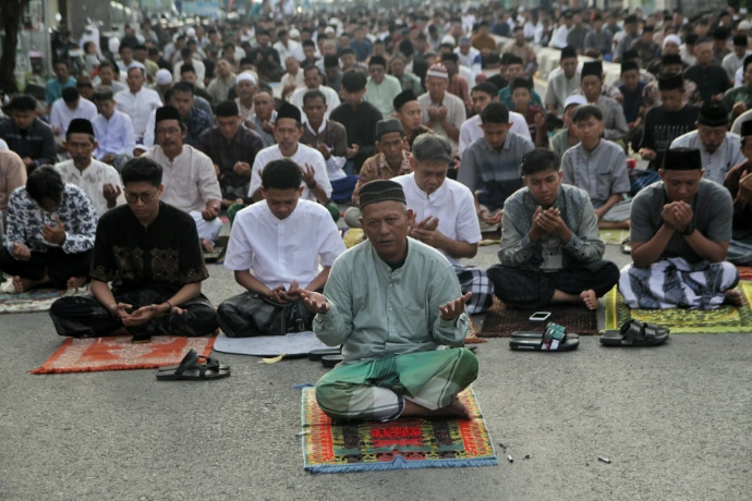 A large group of men praying together outdoors